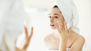Fille applique le sérum de traitement de l'acné dans le miroir.